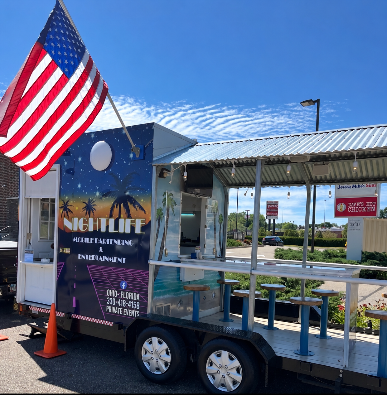 Nightlife mobile bar set up during the day with an American flag